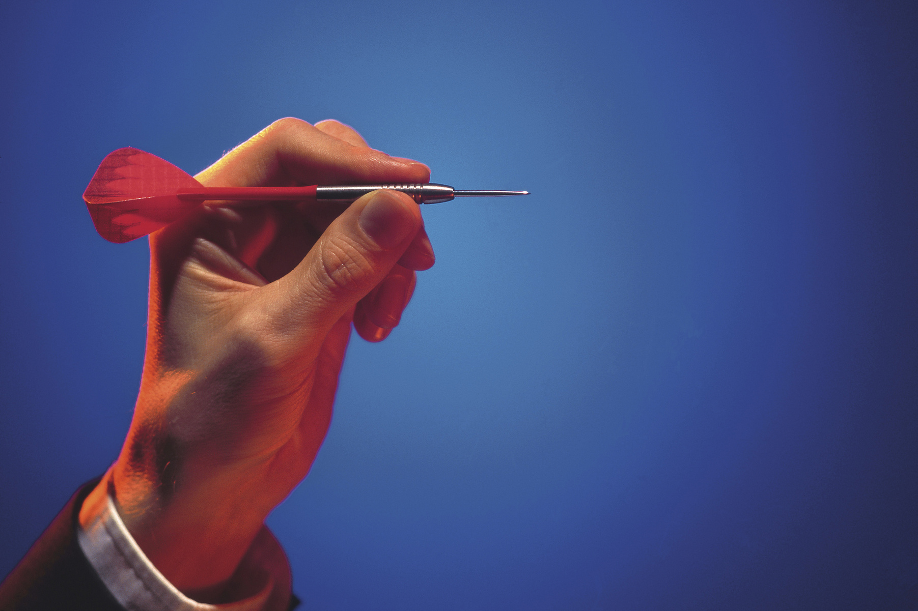 Man's hand aiming dart